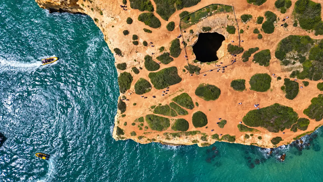 Algarve coastline from above, with a sea cave opening in the cliff and turquoise water